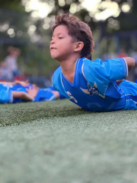 Niño de Chuter FC descansando sobre la grama antes de entrenar