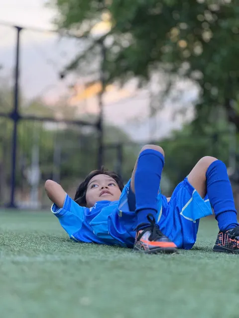 Niño de Chuter FC recostado en la grama tras el entrenamiento